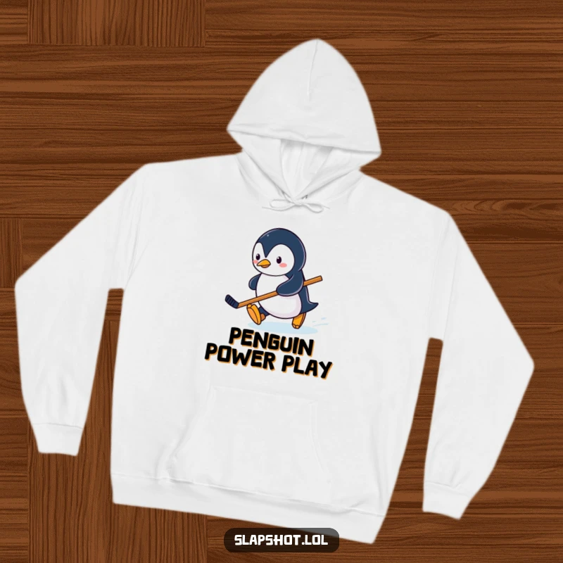 Funny penguin character sliding on ice with a hockey stick, cozy and fun winter-themed hoodie.